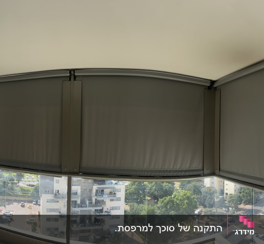 התקנת סוככי מסך זיפ אפורים במרפסת עם מעקה זכוכית